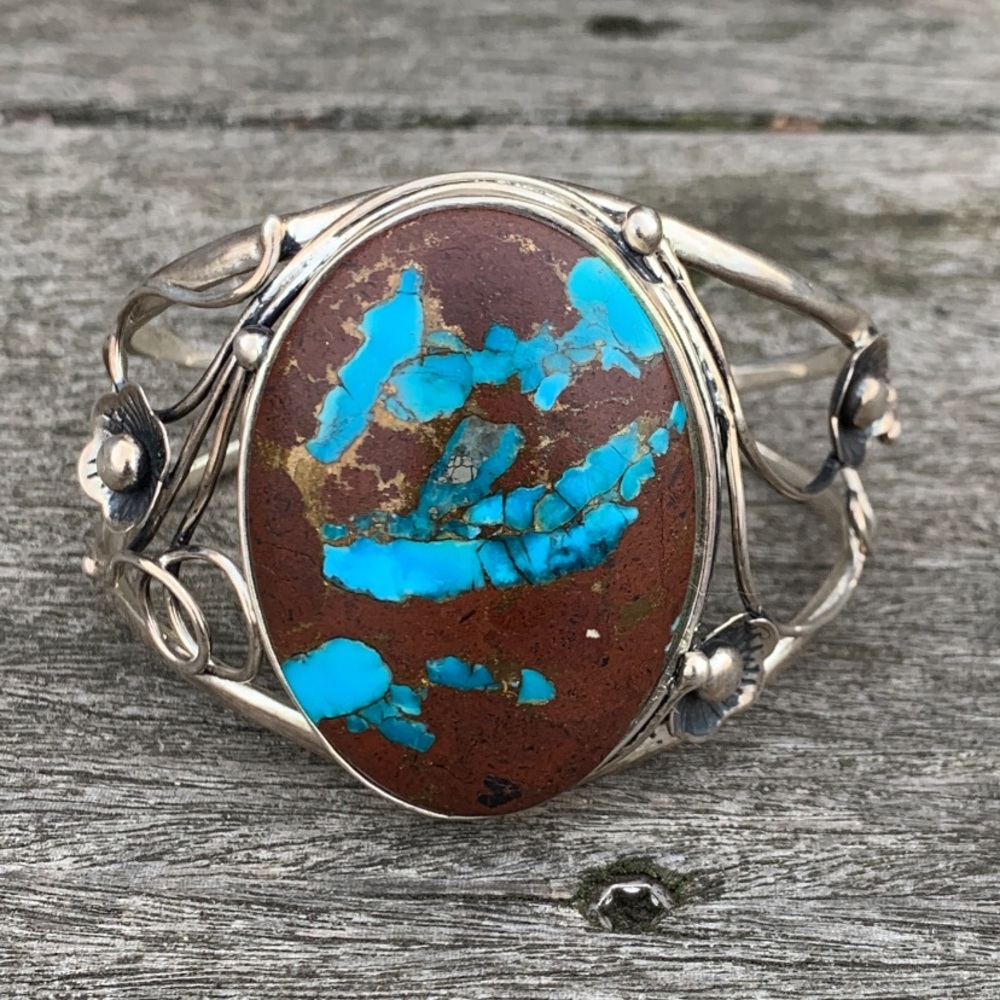 Silver bracelet with beautiful stone and flower details on side.